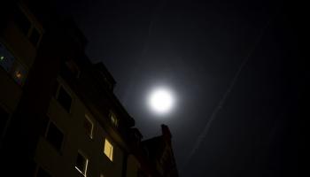 Zu sehen ist eine Straße bei Nacht mit einem hellen Mond